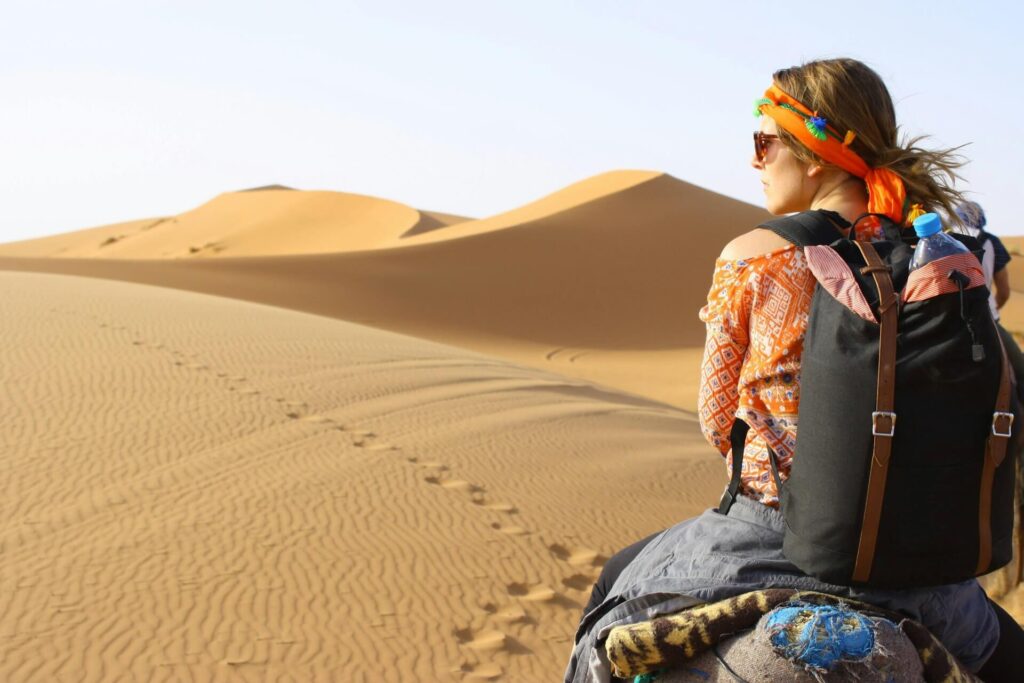 solo female traveler riding camel in desert